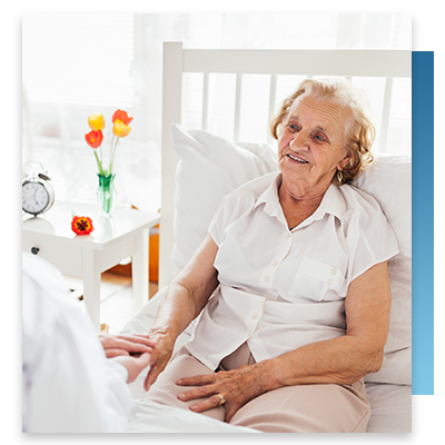An elderly woman in her bed speaking with a nurse