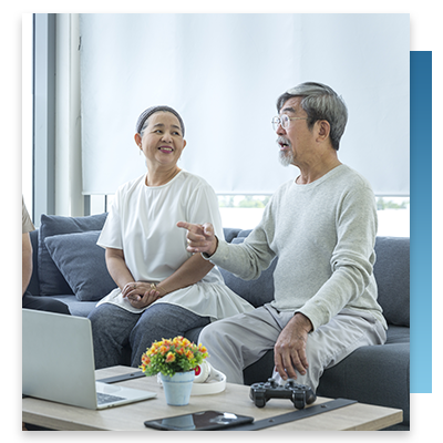 A laptop, headphones and video game controller on a coffee table in a elderly man's room