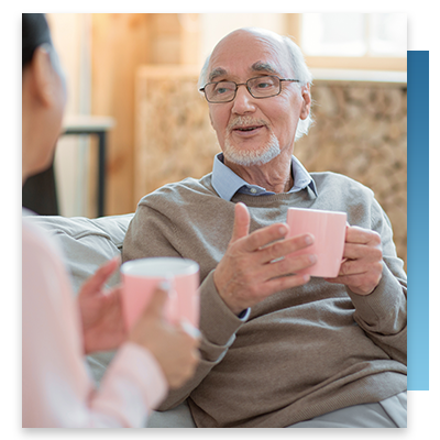 A senior enjoying a cup of coffee with a nurse