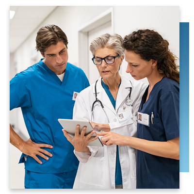 A doctor and two nurses looking at a tablet while in a hospital hallway