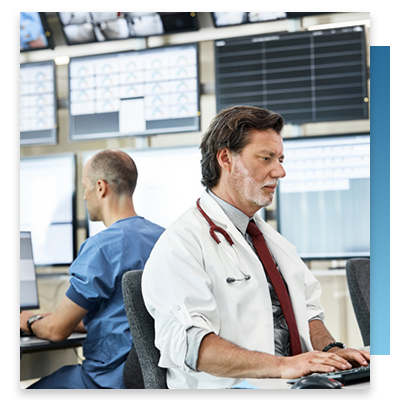 A doctor sitting in a hospital control room looking at a computer