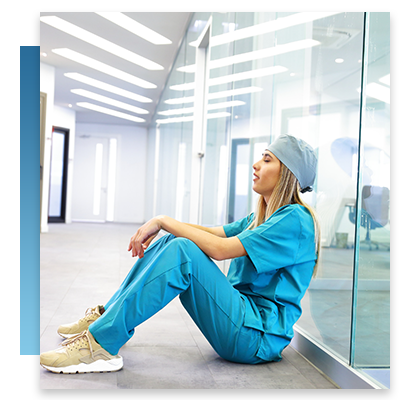 A tired nurse sitting against a wall