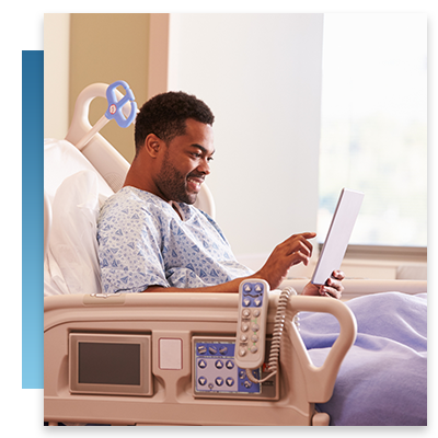 A patient in a hospital bed smiling while using a tablet