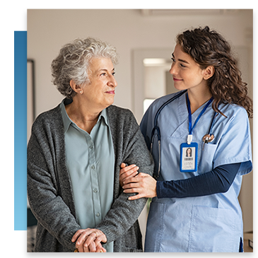 A nurse looks at an elderly patient with care as they walk together