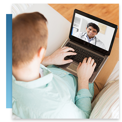 A man on his couch at home chatting with a doctor on his laptop