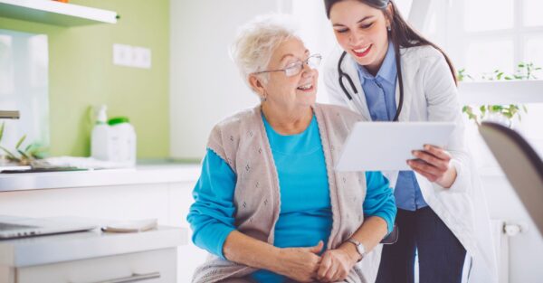 A doctor and older patient look at a tablet together