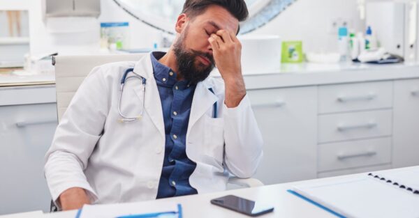 A doctor holding the bridge of his nose because he is tired
