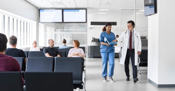 A doctor and nurse walking through a hospital waiting room
