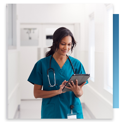 A nurse looking at a tablet in a hospital hall