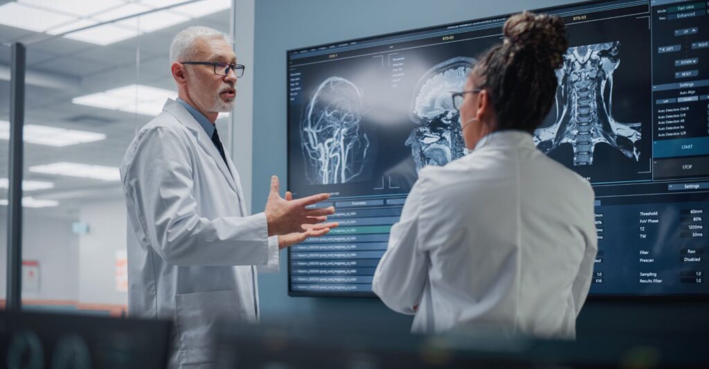 Two doctors discussing treatment in front of a digital whiteboard