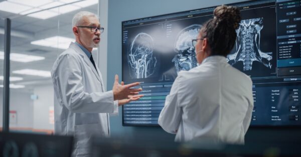 Two doctors discussing treatment in front of a digital whiteboard