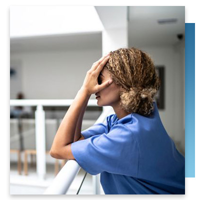 A nurse standing outside with her head in her hands