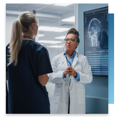 A doctor speaking to a nurse in front of a digital screen