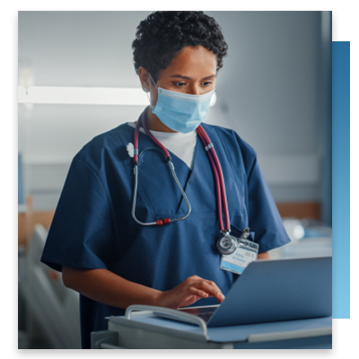 A nurse on a computer in front of hospital beds