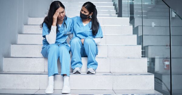 A tired nurse being consoled by another nurse
